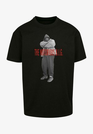 Melna T-kreklu ar pelēku grafiku, kurā attēlots cilvēks kapuces jakā, ar rokām krustu, apakšā ir uzraksts "THE NOTORIOUS B.I.G." sarkanā krāsā.