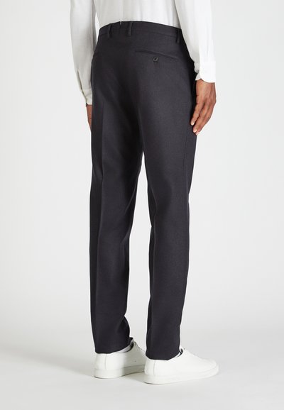 Granatowe spodnie o prostym kroju, uszyte z teksturowanej tkaniny. Posiadają tylnią kieszeń zapinaną na guzik, zestawione z białymi trampkami.