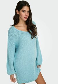 Gaiši zils pārlielā izmēra adīts džemperis ar platām piedurknēm, apaļu kakla izgriezumu un mīkstu tekstūru. Piedāvā vaļēju pieguļumu, kas sniedzas līdz vidus augšstilbam.