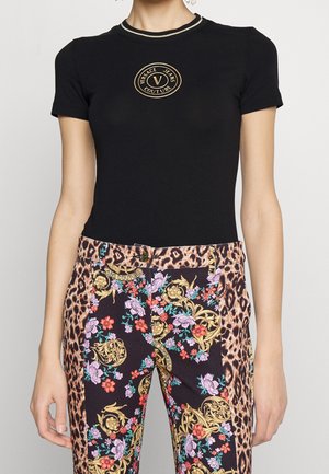 Czarny dopasowany t-shirt z krótkim rękawem z złotym wyszywanym logo "Versace Jeans Couture", zestawiony z kwiatowymi i panterkowymi spodniami.