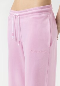 Roze joggers van zachte stof met een elastische tailleband, een trekkoord met uiteinden en "mijn luierbroek" geborduurd op de zijkant.