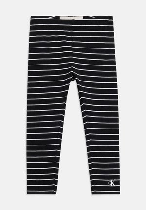 Sorte leggings med tynde hvide vandrette striber og et lille hvidt "cK" logo nær den nederste kant på højre ben.