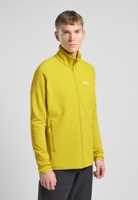 Geel fleece jack met een hoge kraag, ritssluiting aan de voorkant en zijzakken. Gladde textuur en aangesloten ontwerp. Merklogo op de borst.