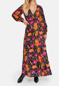 Robe maxi en tissu noir ornée de motifs floraux vibrants en orange et violet, décolleté en V profond, manches longues et silhouette fluide.