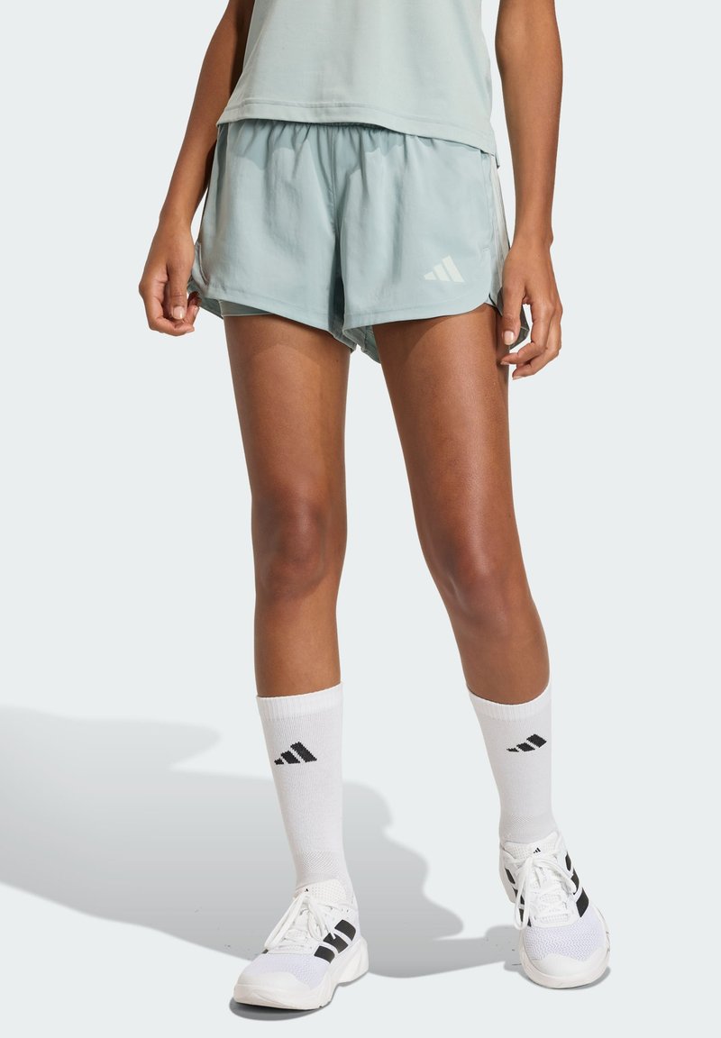 Light blue athletic shorts with an elastic waistband, a white Adidas logo, paired with black and white knee-high socks and white sneakers.