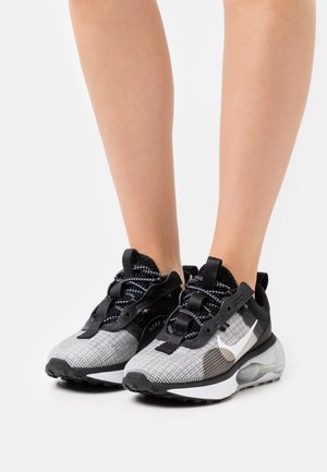 Černé a šedé sportovní boty s síťovaným svrškem, texturovanými vzory, silnou bílou podrážkou a černými tkaničkami. Zvláštní logo swoosh na boku.