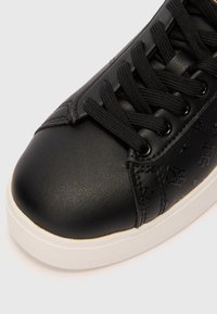 Czarne sneakersy z gładką skórzaną cholewką, teksturowanym akcentem, okrągłym noskiem i kontrastującą białą gumową podeszwą; wyposażone w czarne sznurówki i wytłoczone detale.