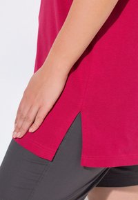 T-shirt in cotone fucsia a maniche corte con fessure laterali, abbinato a pantaloni corti grigio scuro. Texture liscia con vestibilità comoda.