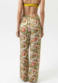 Weite Hose mit einem mehrfarbigen Muster aus Blättern und Formen in Grün, Pink und Braun, gefertigt aus leichtem Stoff mit einem elastischen Bund.