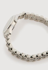 Orologio in acciaio inossidabile argento con cassa rotonda, lunetta texturizzata e bracciale a maglie che presenta segmenti arrotondati e piatti.