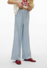 Lyseblå bukser med vide ben og vertikale hvite og mørke striper. Laget av glat stoff med elastisk midjebånd. Brukt med røde leiligheter.