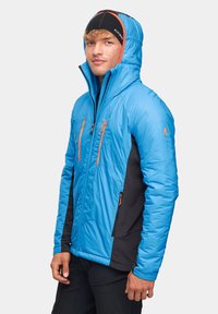 Niebieska kurtka ocieplana z kapturem, czarne panele boczne, pomarańczowe zamki błyskawiczne i logo. Charakteryzuje się gładką teksturą i dopasowanym krojem.