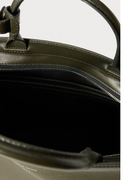 Mala de mão em pele verde caqui com textura suave, fecho com zíper e bolso interior. Apresenta alças resistentes e detalhes de costura subtil.