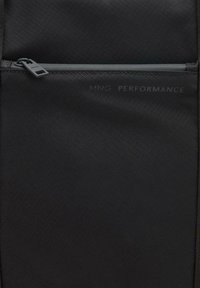 Sort rygsæk med en struktureret overflade, der har en lynlåslomme og "MNG PERFORMANCE" branding i diskret tryk.