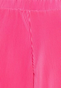 Rosa plisserad tyg som visar vertikala ränder, slät till texture, och ett elastiskt midjeband för komfort och passform.