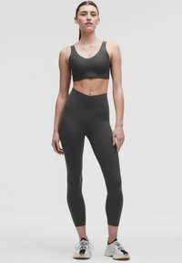 Tumši pelēki sporta krūšturi un augstām jostasvietām legingi, kas izgatavoti no elastīga auduma. Krūšturis piedāvā plašas siksnas, bet legingiem ir gluda virsma.