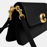Μαύρη δερμάτινη τσάντα χειρός με χρυσό κούμπωμα σε σχήμα γράμματος C και χρυσά μεταλλικά στοιχεία που συνδέουν το δερμάτινο λουράκι με την τσάντα.