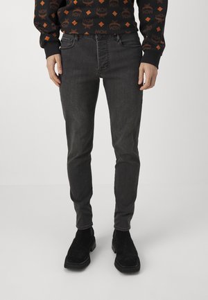 Jeans in denim grigio scuro con una vestibilità slim, dotati di cinque tasche e cuciture a contrasto. Indossati con stivaletti neri a tessuto.