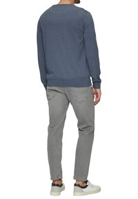 Grauer Pullover mit Rundhalsausschnitt, strukturierter Stoff und langen Ärmeln. Kombiniert mit hellgrauen, schmal geschnittenen Jeans und weißen Sneakers.