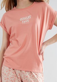 Lichtroze t-shirt met korte mouwen, voorzien van een witte "GREAT DAY" grafiek, gemaakt van zachte katoen. Casual fit met opgerolde mouwen.