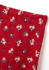 Rode stof met een bloemenprint, met kleine roze en blauwe bloemen en groene bladeren. Zachte textuur, elastische bovenkant.