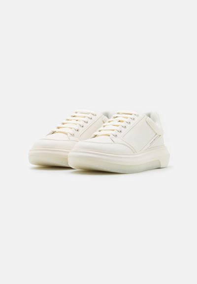 Bele superge z gladkim sintetičnim zgornjim delom, ravnimi vezalkami in debelim, polprozorni podplatom. Imajo diskreten stranski logo in podrobnosti šivanja.