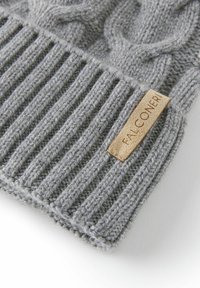 Grå strikket hat med ribbet design og tykke kabelstrik. Inkluderer en beige læderlabel med teksten "FALCONERI."