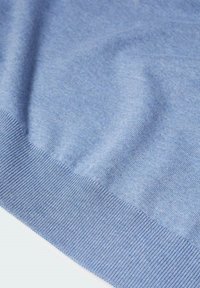 Tessuto lavorato a maglia di colore azzurro chiaro con bordo a coste, che mostra una texture morbida e pieghe delicate.