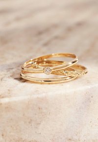 Ensemble de trois anneaux en or avec un design tressé texturé, un bandeau lisse et un avec un accent en diamant central.