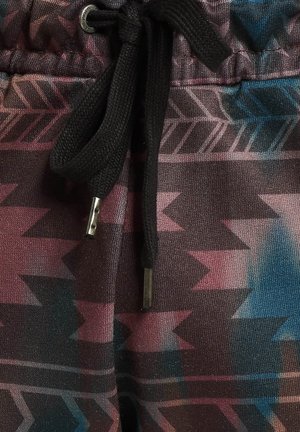 Joggeurs à motifs présentant un design géométrique multicolore dans des teintes de rose, bleu et noir, avec un cordon de serrage noir et des accents métalliques.