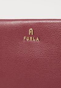 Burgunderfarget lær lommebok med teksturert overflate og preget gull "FURLA"-logo. Har et glatt, strømlinjeformet design med minimalt med utstyr.