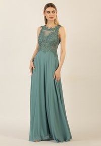 Teal evening gown featuring a sleeveless design, intricate lace detailing on the bodice, and flowing fabric. Smooth texture and elegant silhouette.