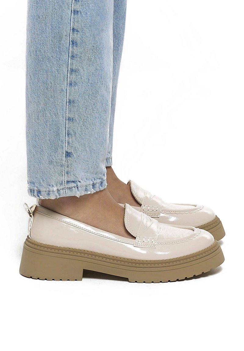 Mocassins en cuir verni beige avec semelles en caoutchouc épaisses portés avec un jean raccourci bleu clair.