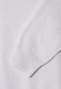 Sezione di maglione a maglia grigio chiaro con polsini a coste. Texture liscia, motivo a macchie sottili e vestibilità classica. Focus sui dettagli delle maniche.