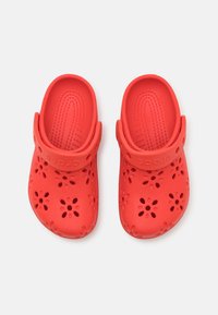 Punane plastikust puukingad, millel on lillemotifi lõikeavad, tekstureeritud sisetald ja tagavöö turvaliseks kinnitamiseks. Sile pind ja vastupidav disain.