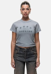 T-shirt cropped grigio in cotone con stampa grafica frontale che riporta la scritta "Good for Nothing" in grassetto con lettere nere a contrasto.