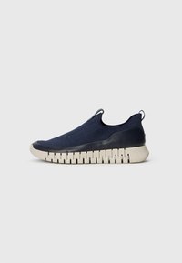 Navy slip-on sneaker with a textured fabric upper, smooth rubber heel, and a flexible, ridged sole in beige. No laces or prominent accents.