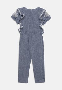 Modrý lněný overal s dekorativními volánkovými rukávy. Obsahuje vyšívané květinové detaily a zip na zadní straně.