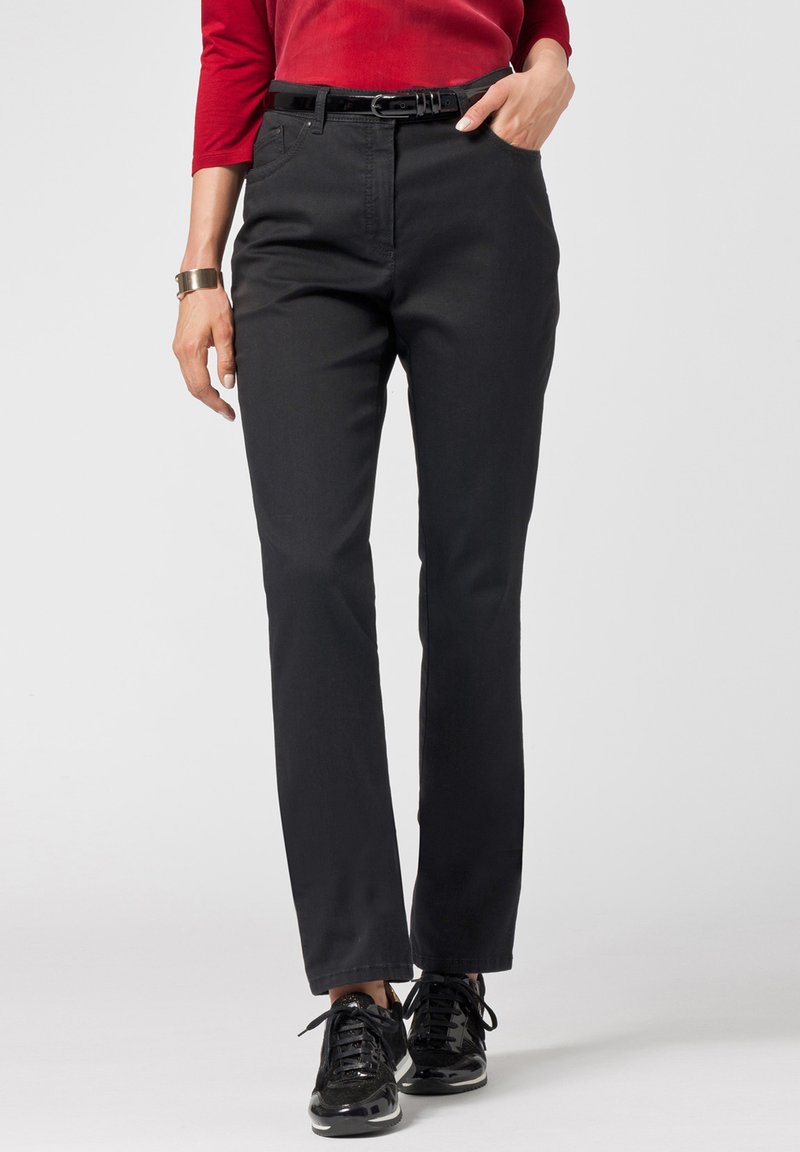 Pantaloni in tessuto nero con design a gamba dritta e una leggera trama, dotati di tasche frontali e una cintura nera. Abbinati a sneakers nere.