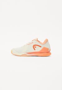 Tennis shoe in light cream with textured mesh upper, peach accents, and distinctive logo. Features a flexible rubber sole for grip.