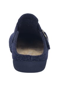 Chaussure slip-on en feutre marine avec un dos ouvert, dotée d'une semelle en liège et d'un accent métallisé décoratif sur le côté. Semelle plate pour un enfilage facile.