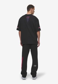 Black cotton oversized t-shirt and matching sweatpants with colorful logo accents; features graphic design on the back and side stripe.