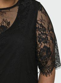 Top nero con maniche corte in pizzo trasparente con motivi floreali, corpo in tessuto testurizzato, scollatura rotonda e dettagli in pizzo intricati.