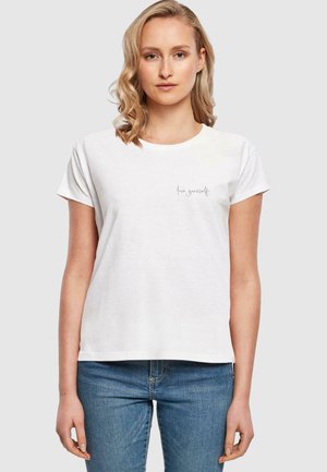 T-shirt en coton blanc à manches courtes, décolleté rond, avec un petit imprimé « live yourself » en gris sur le côté gauche.
