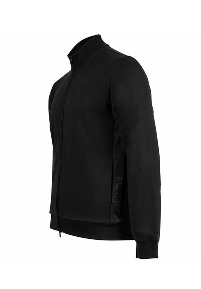 Giacca nera con zip realizzata in tessuto liscio. Presenta un colletto rialzato, polsini a coste, vestibilità slim e dettagli del logo discreti sulla manica.