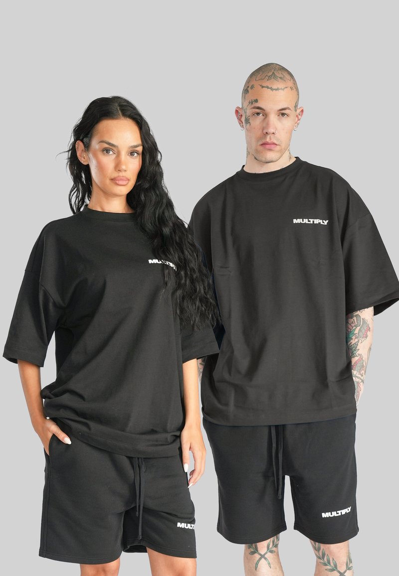 T-shirt e pantaloni corti neri in cotone oversize con il logo "MULTIPLY". Presentano maniche corte e una vestibilità rilassata. Texture liscia, senza motivi.
