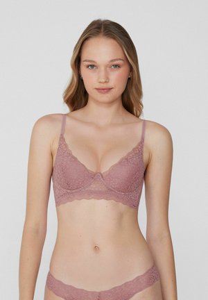 Bralette en dentelle et thong assorti en rose poussiéreux. Motif floral délicat, bords festonnés, bretelles ajustables et texture légèrement transparente.