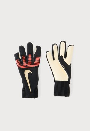 Pár čierno-krémových brankárskych rukavíc Nike s červenými pruhmi na zadnej strane a veľkým logom Nike na ľavej rukavici.
