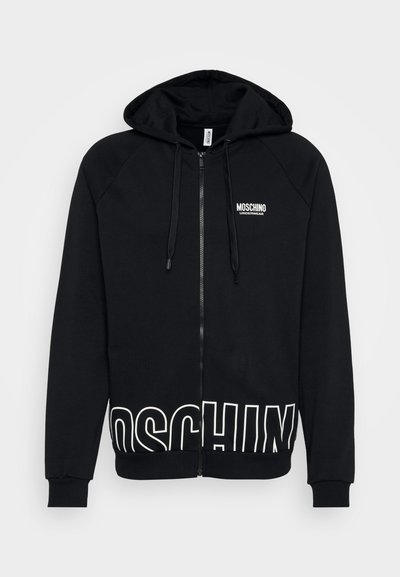 Fekete cipzáras kapucnis pulóver, pamut keverékből készült. Húzózsinóros kapucnival, raglán ujjal és nagy fehér "MOSCHINO" logóval az alján.