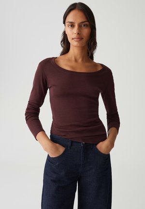 Langarm, bordeauxkleurig top met een brede halslijn en een slim fit, gecombineerd met donkerblauwe spijkerbroek met voorzakken en een klassiek ontwerp.